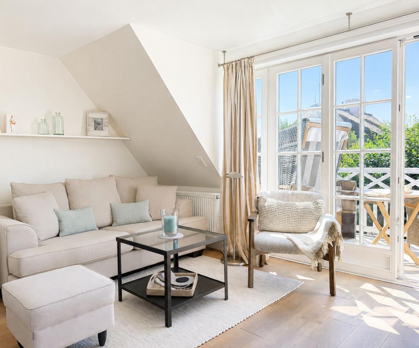 Wohnzimmer mit Sofa, Sessel und Terrasse. Dachfenster und Holzboden.