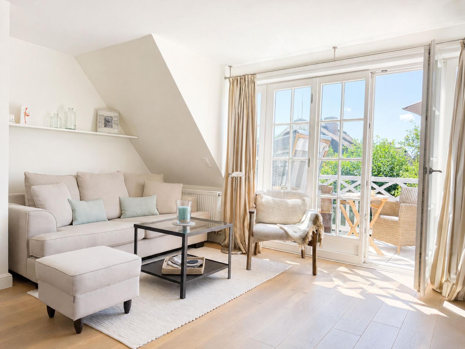 Wohnzimmer mit Sofa, Sessel und Terrasse mit Blick auf Grünflächen.