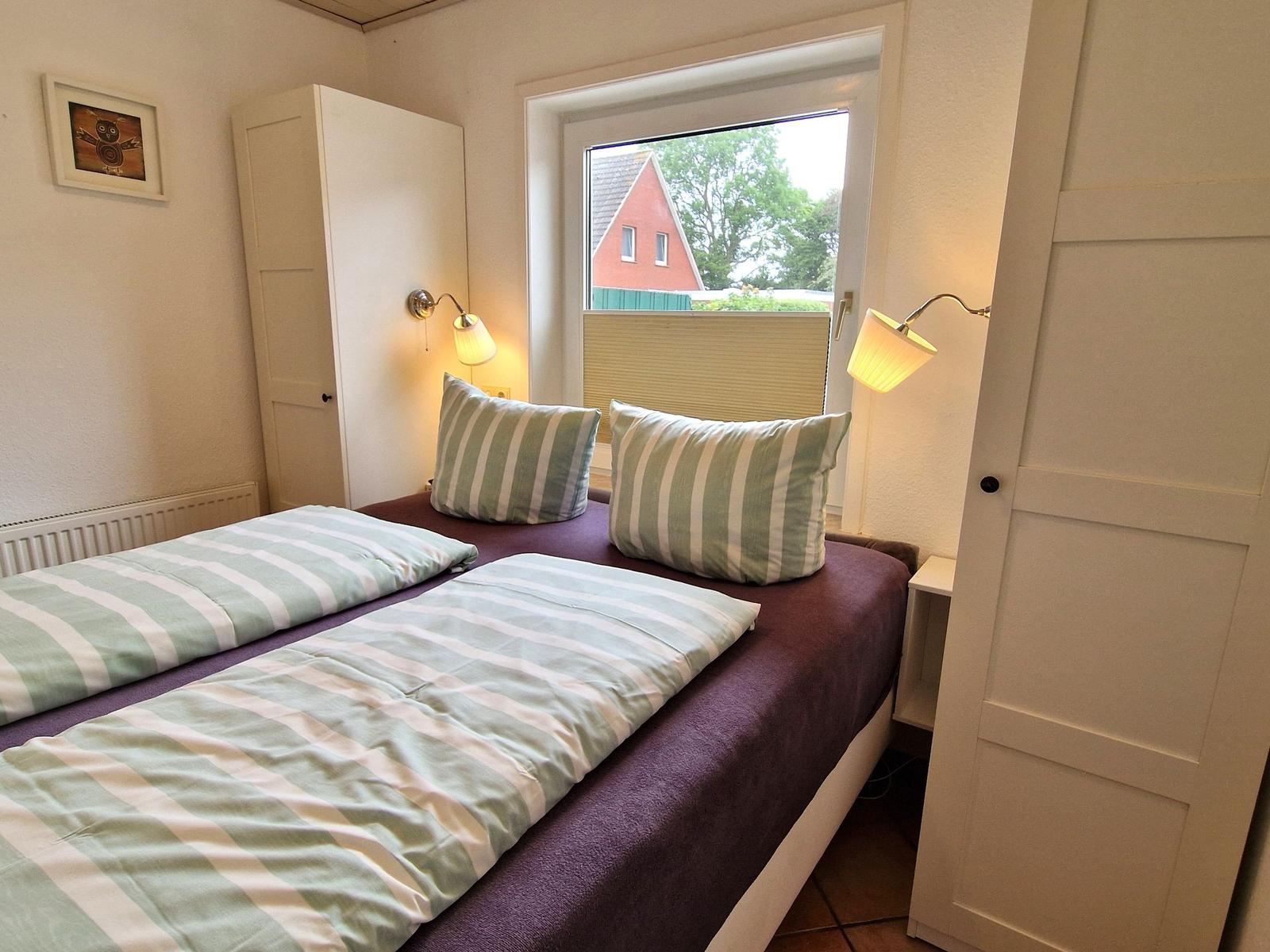 Schlafzimmer mit Doppelbett, Fenster und Wandlampen.