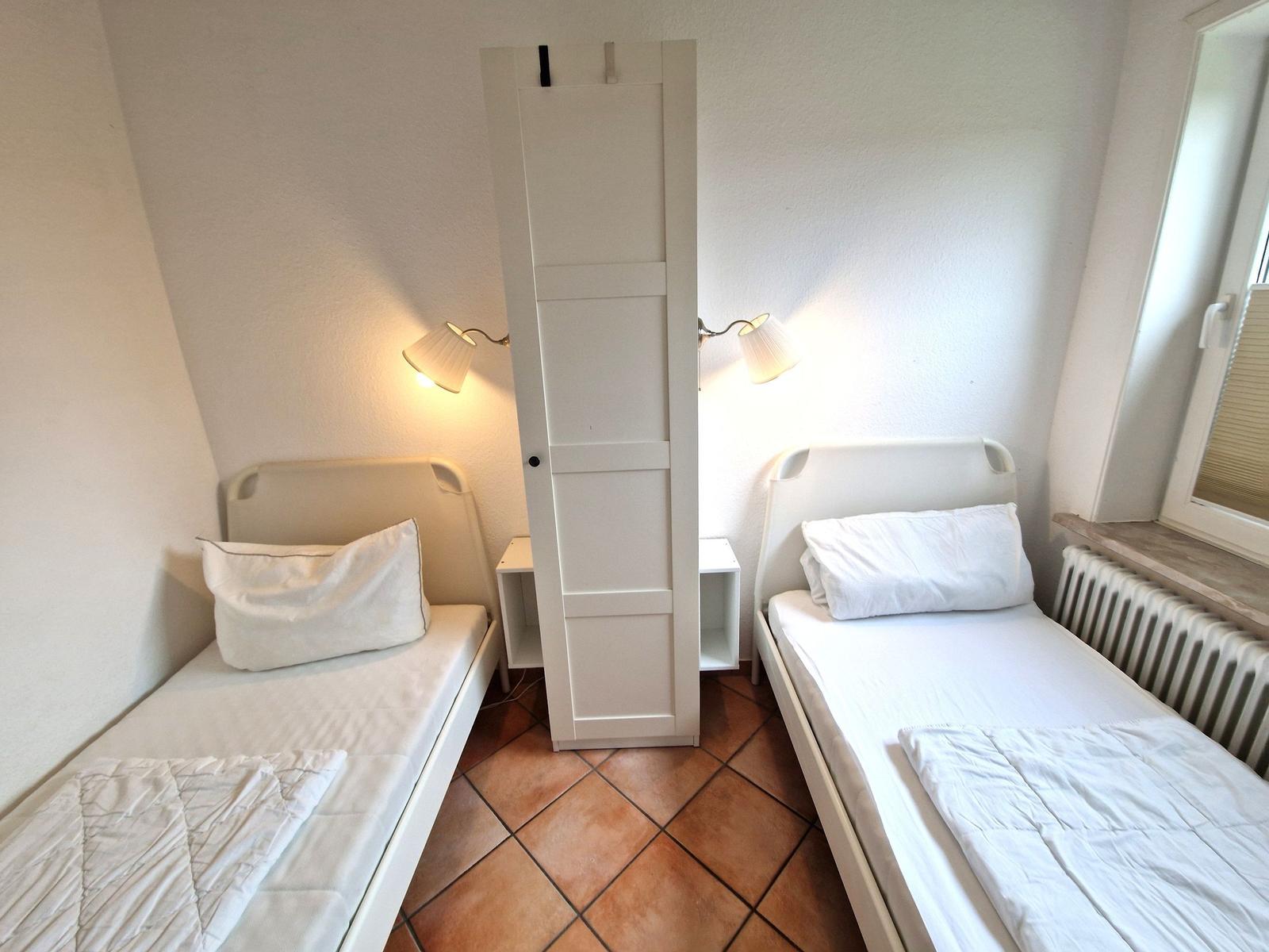 Zwei Einzelbetten mit weißen Bettwäschen und Nachttischen mit Lampen.