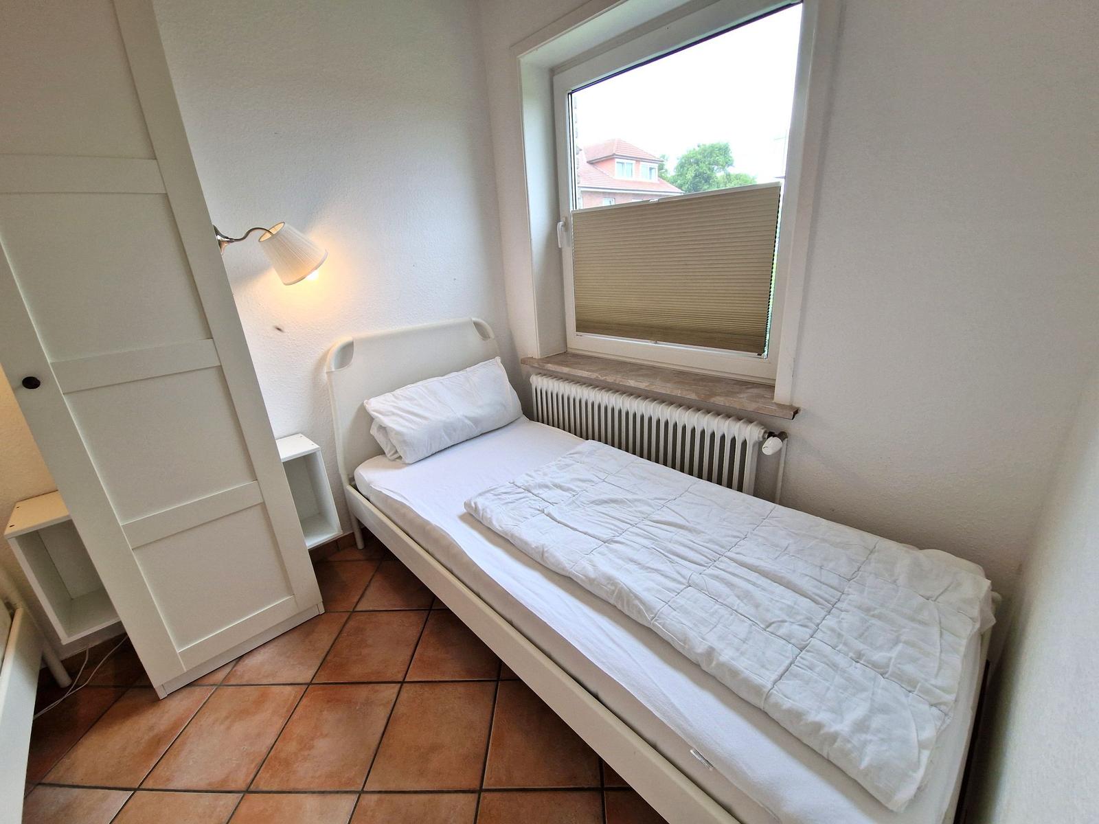 Ein Schlafzimmer mit einem Bett, einem Fenster und einer Stehlampe.