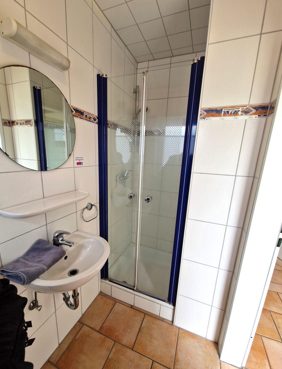 Badezimmer mit Dusche, Waschbecken und Spiegel