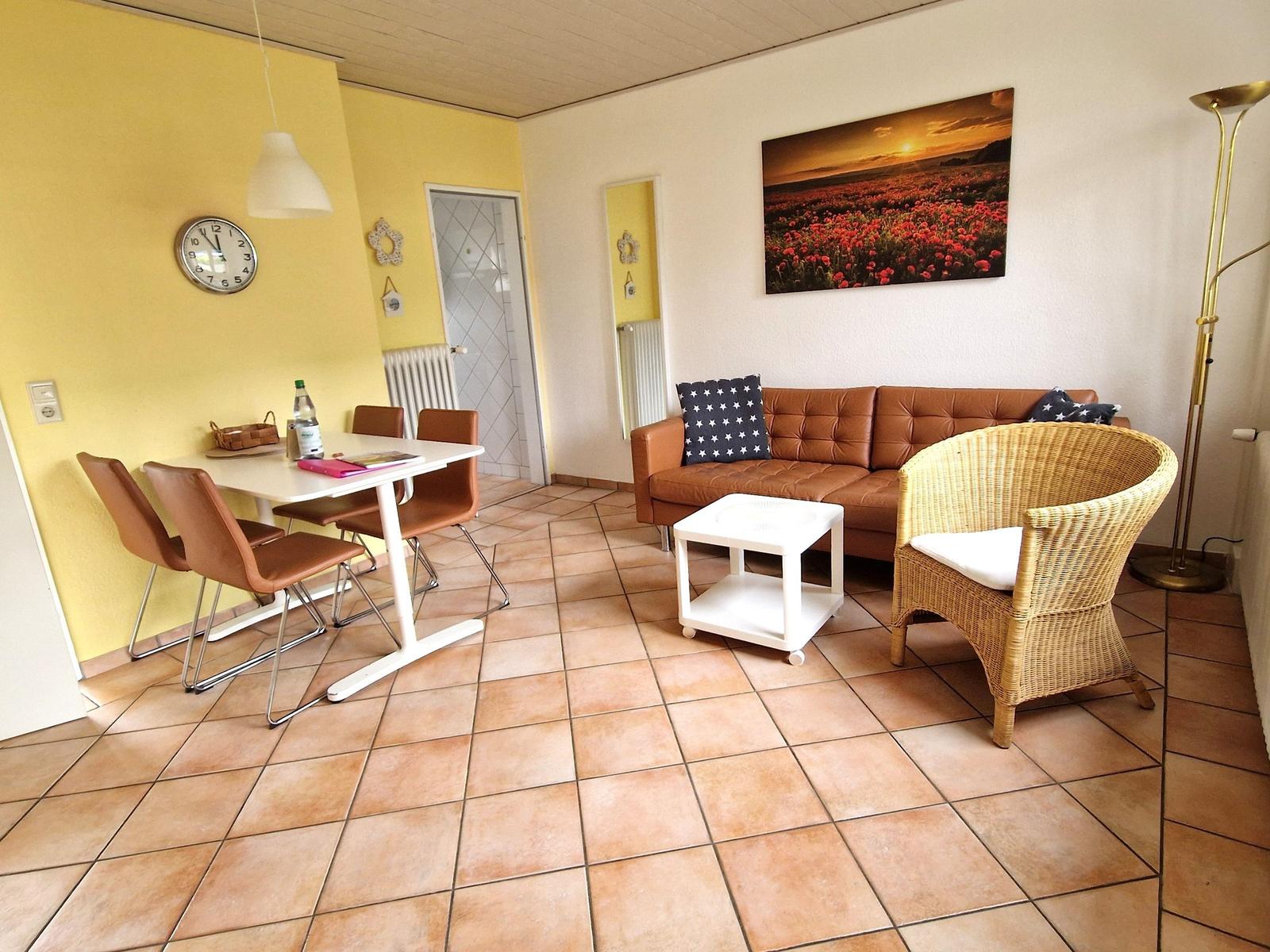 Wohn- und Essbereich mit braunem Sofa, Esstisch und Wandbild.