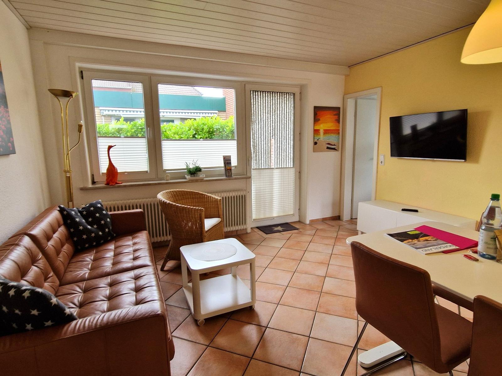 Wohn- und Essbereich mit Sofa, Esstisch und Fernseher an der Wand.