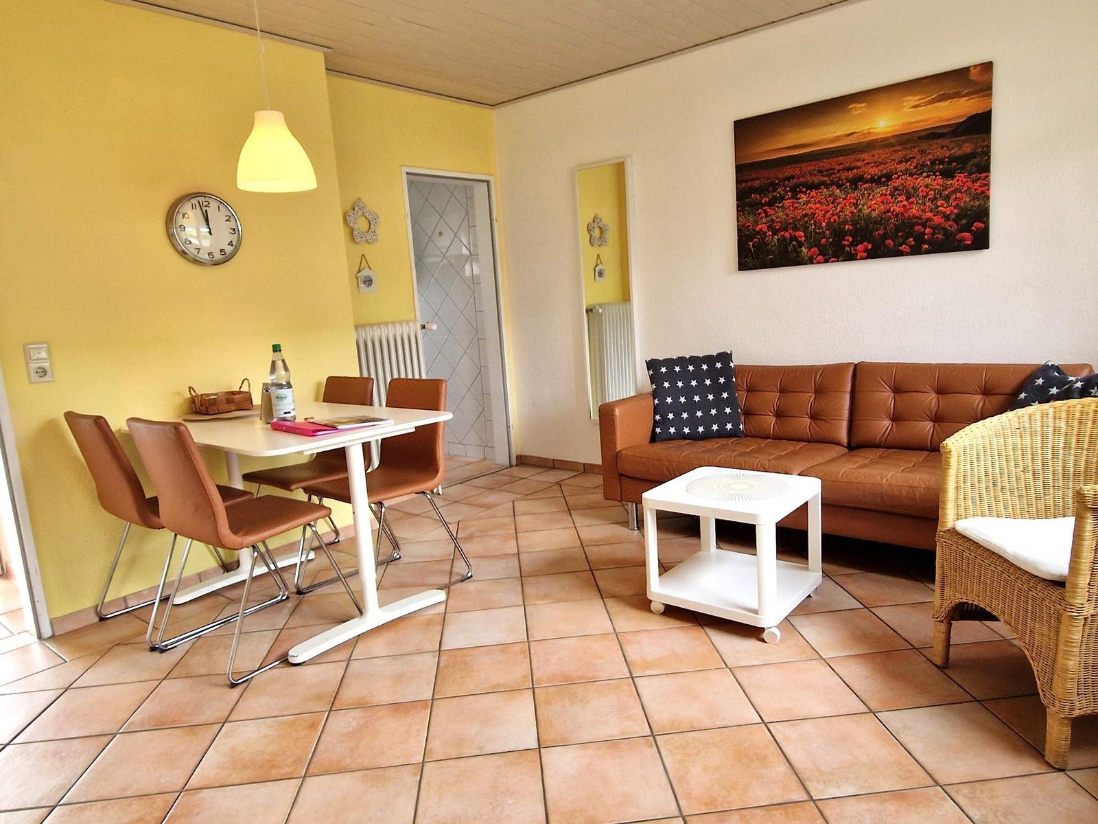 Wohn- und Essbereich mit braunem Sofa, Esstisch und Wandbild.
