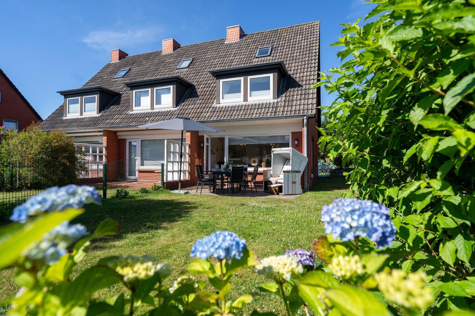 Haus mit Garten, Terrasse und Essbereich unter freiem Himmel.