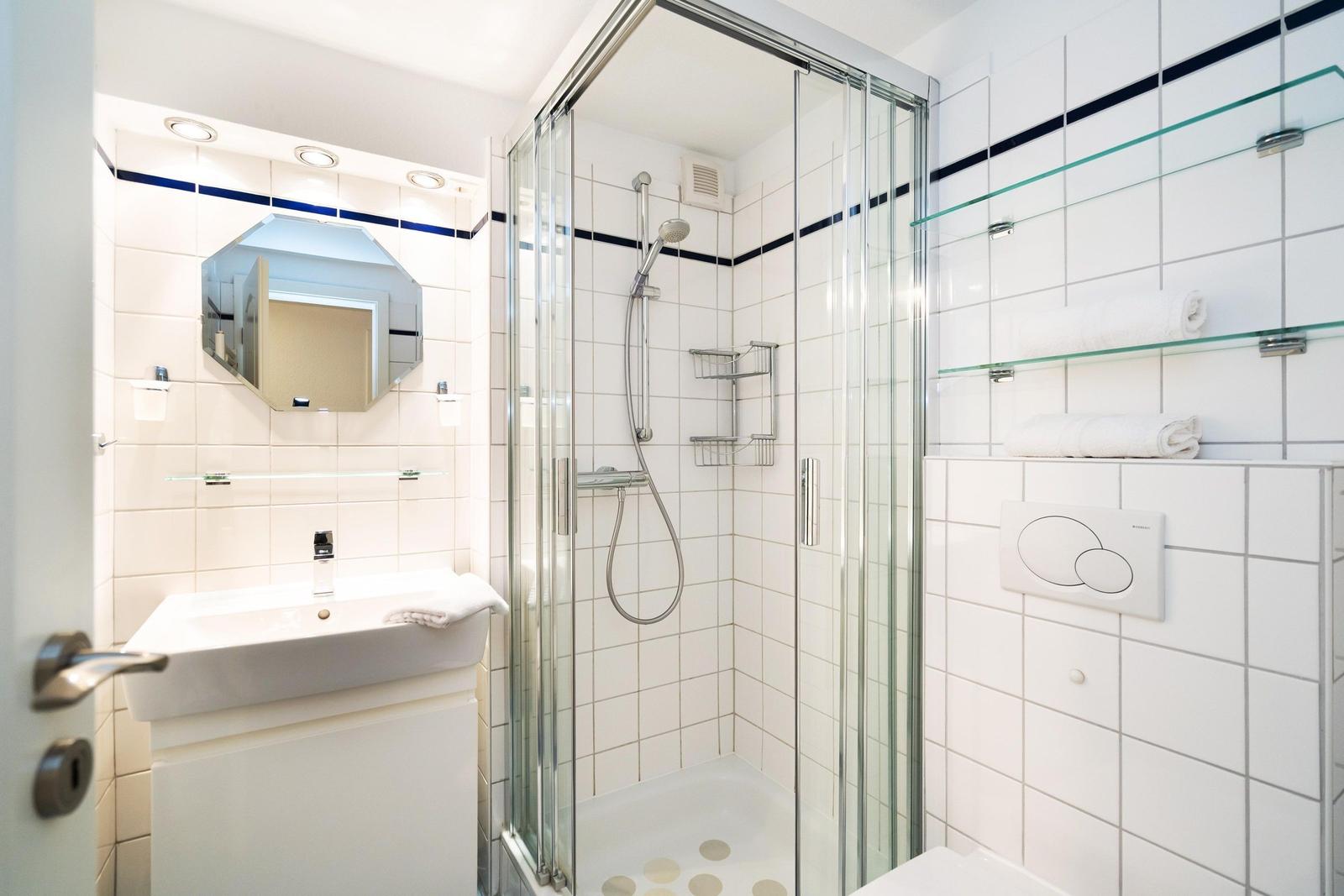 Badezimmer mit Dusche, Waschbecken und Spiegel.