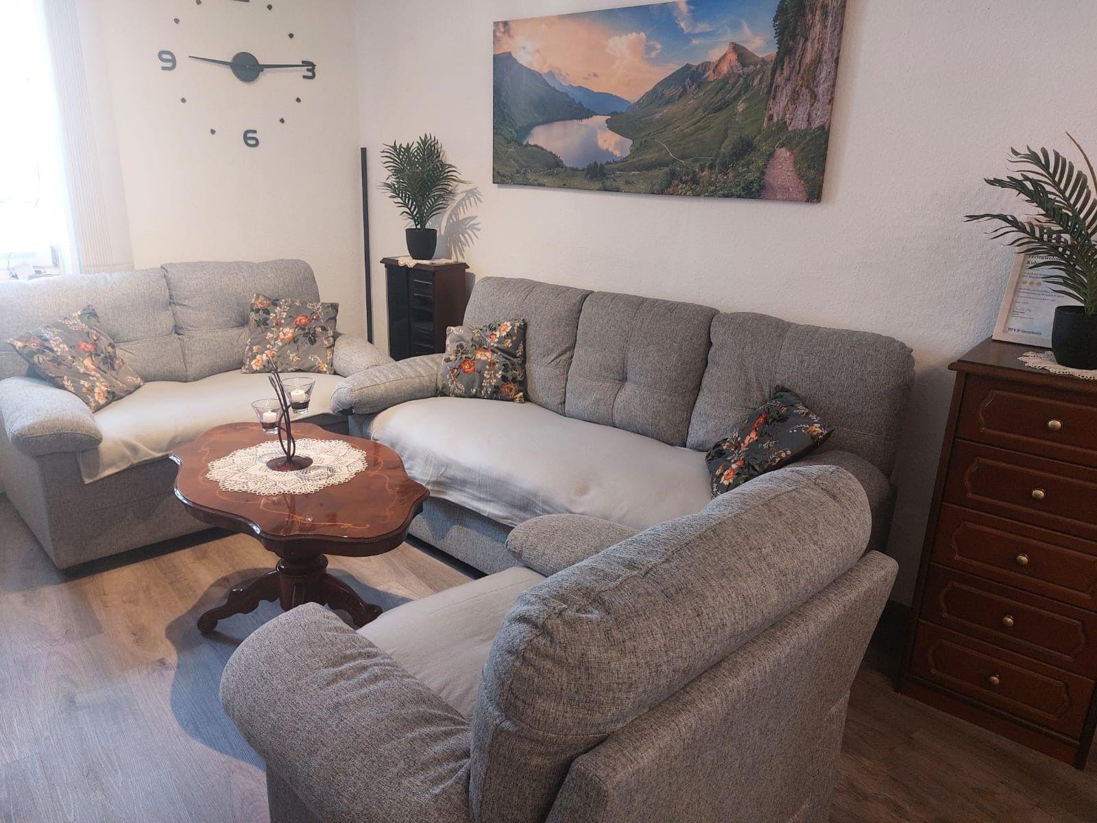 Ein Wohnzimmer mit grauem Sofa, Holztisch und Wandbild.