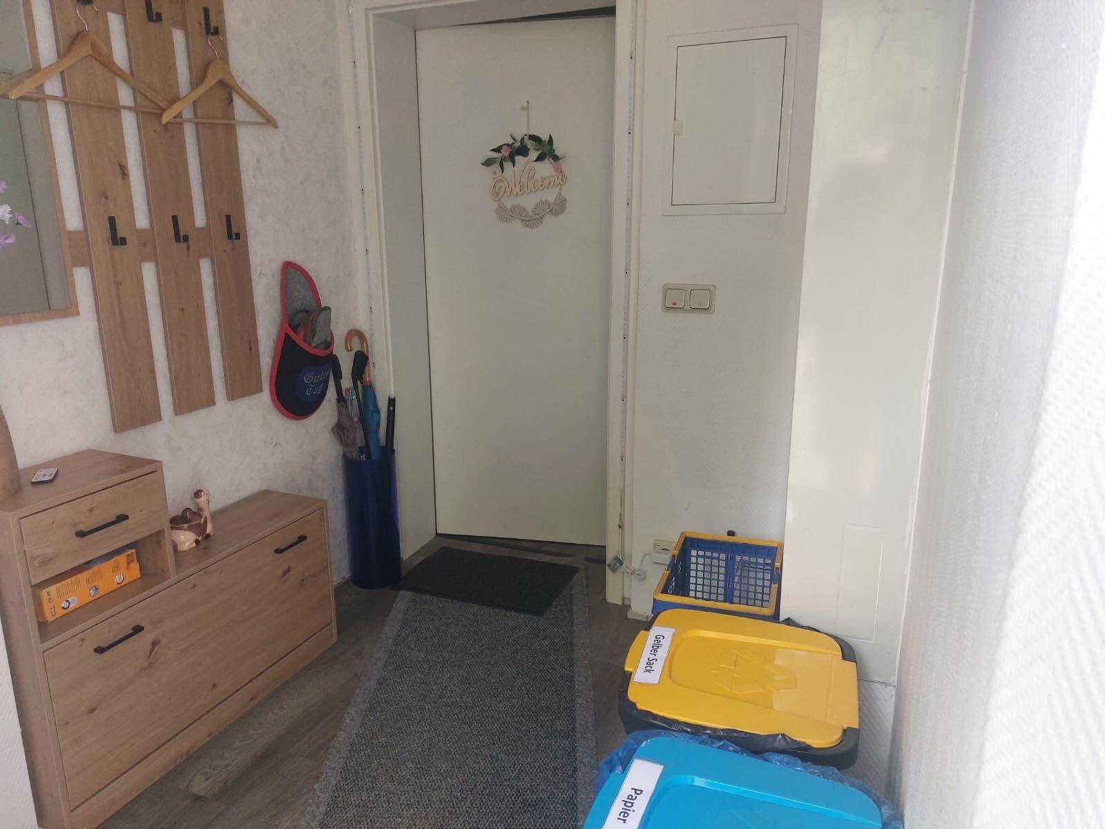 Eingangsbereich mit Schuhschrank, Haken und Müllcontainern.