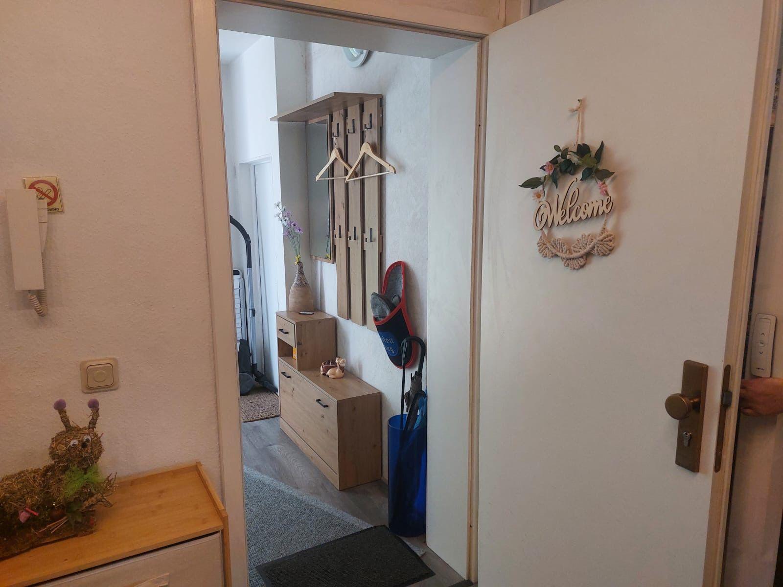 Eingangsbereich mit Schuhgarderobe, Willkommensschild und Kleiderschrank.