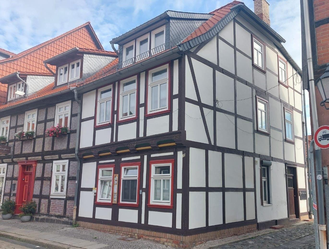 Fachwerkhaus mit rotem Dach und weißen Wänden an einer Straße.