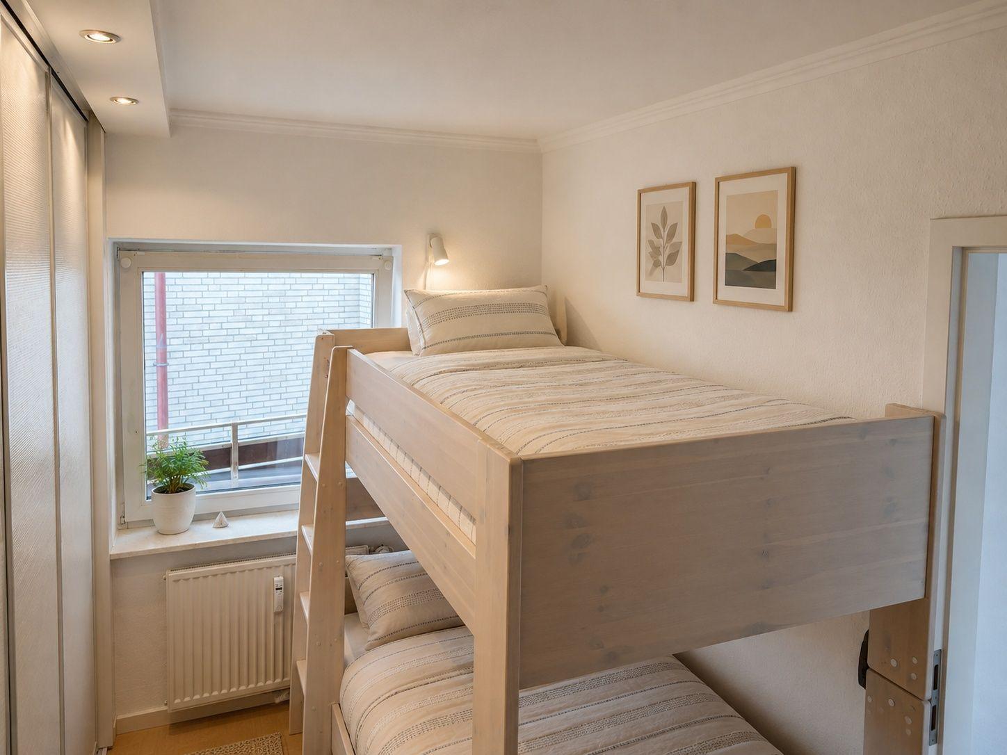 Ein Schlafzimmer mit einem Doppelstockbett, einem Fenster und zwei Bildern an der Wand.