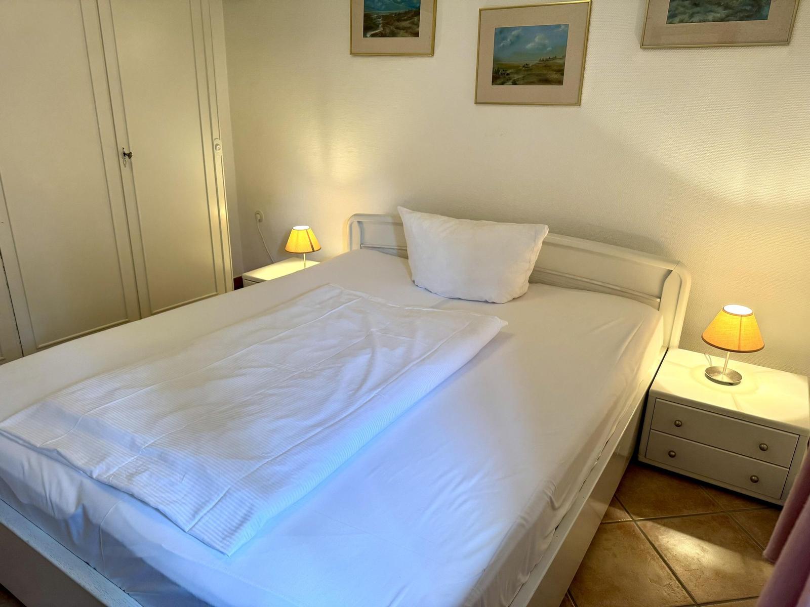 Bedroom with bed, nightstands, and lamps on the wall.