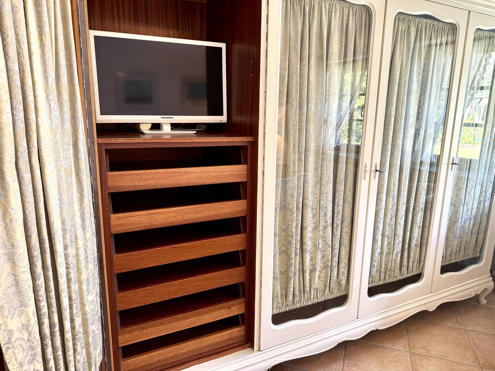 Cabinet with TV and wooden shelves, full-length curtains