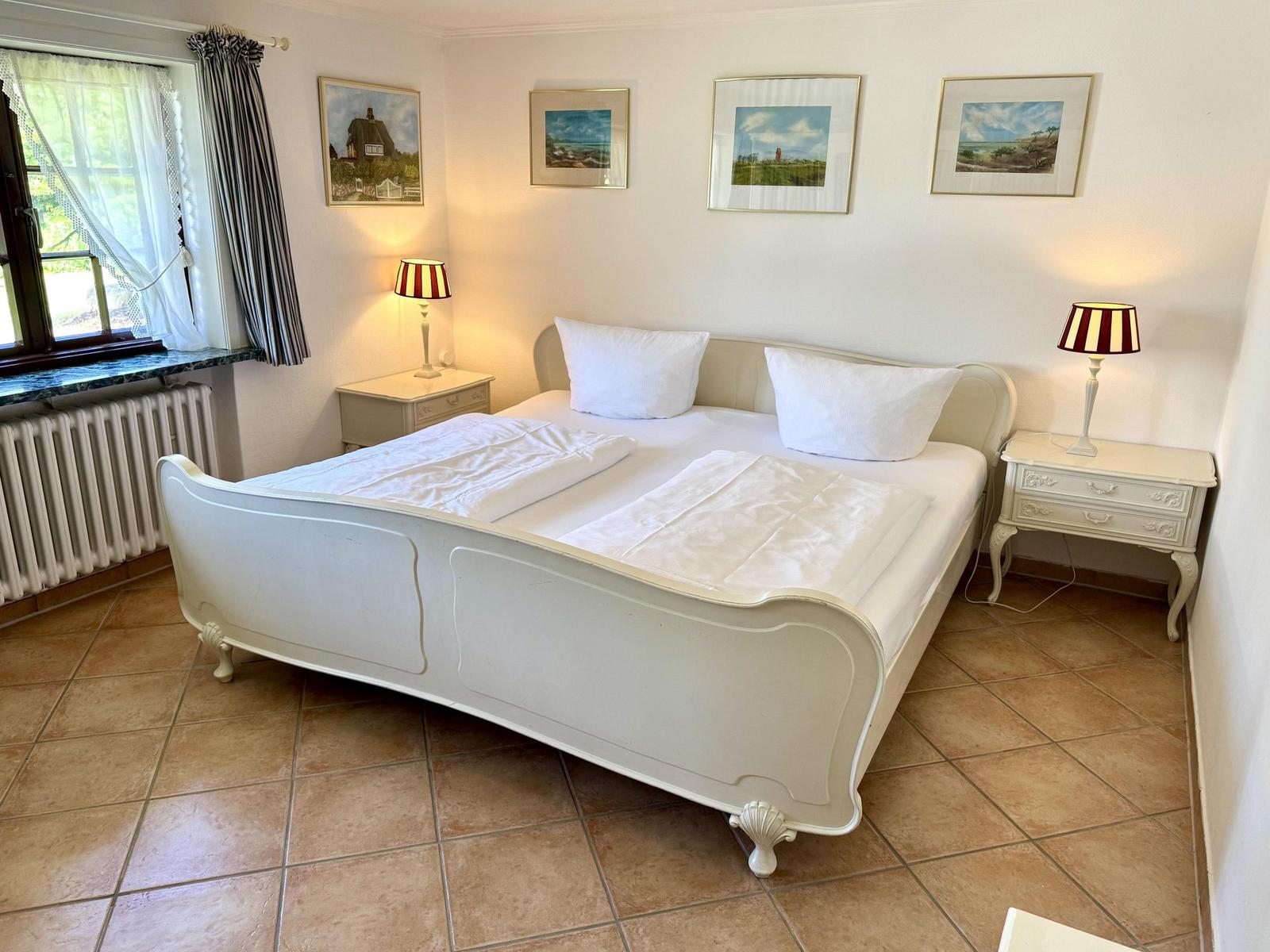 Bedroom with white bed, two nightstands, and window with curtains.