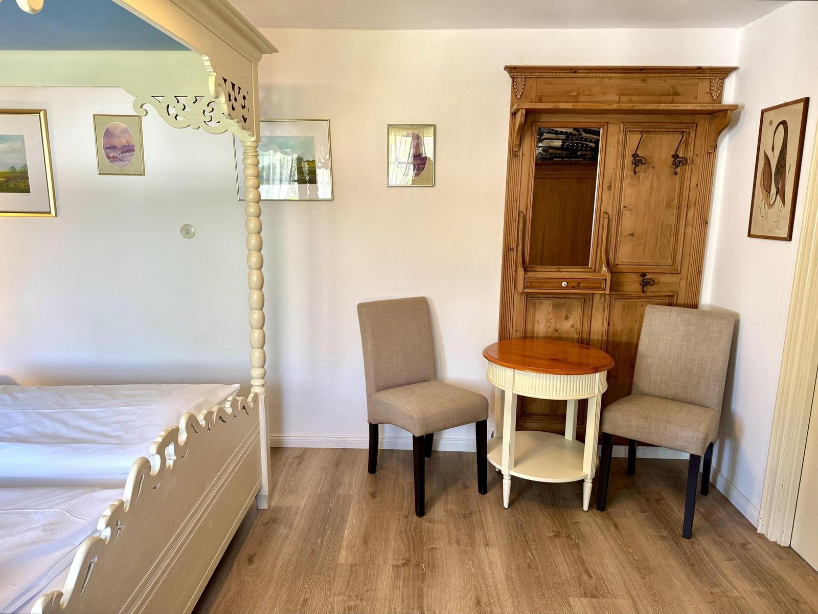 Bedroom with bed, wardrobe, and seating area.