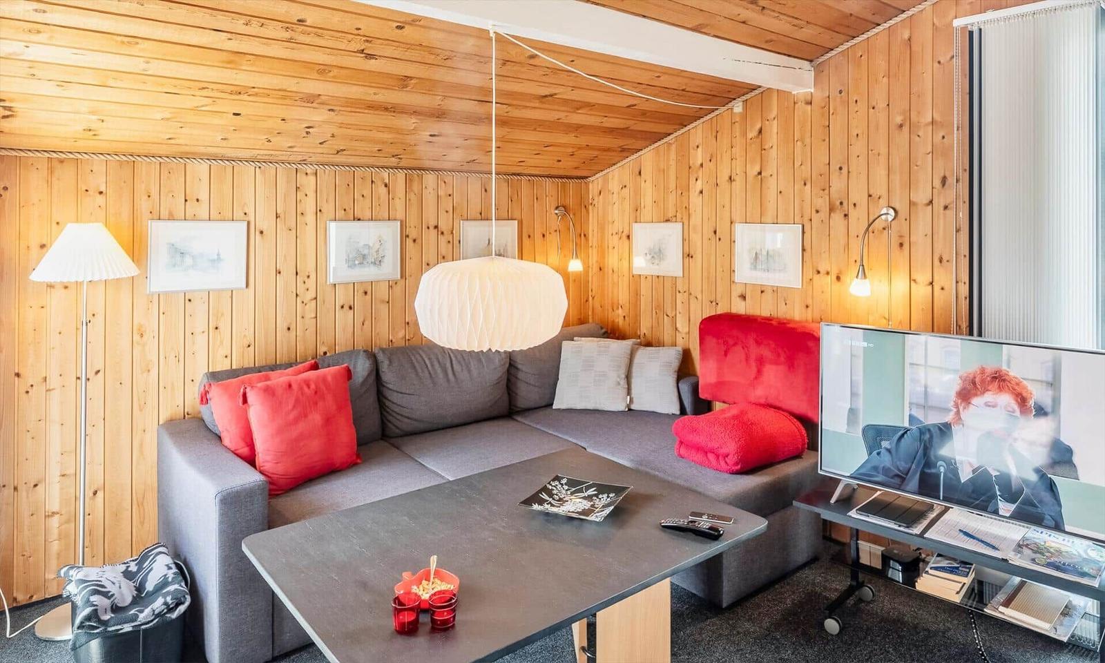 Wohnzimmer mit Holzwand, Sofa, Couchtisch und Fernseher.