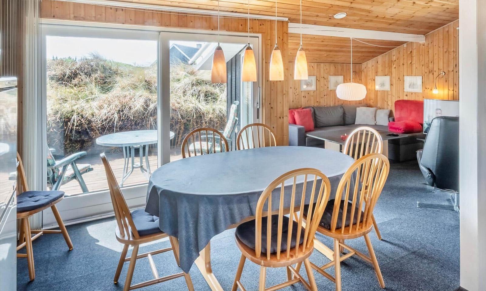 Essbereich mit runder Tisch und Holzstühlen. Durchgang zum Wohnzimmer mit Sofa und Blick auf die Terrasse.