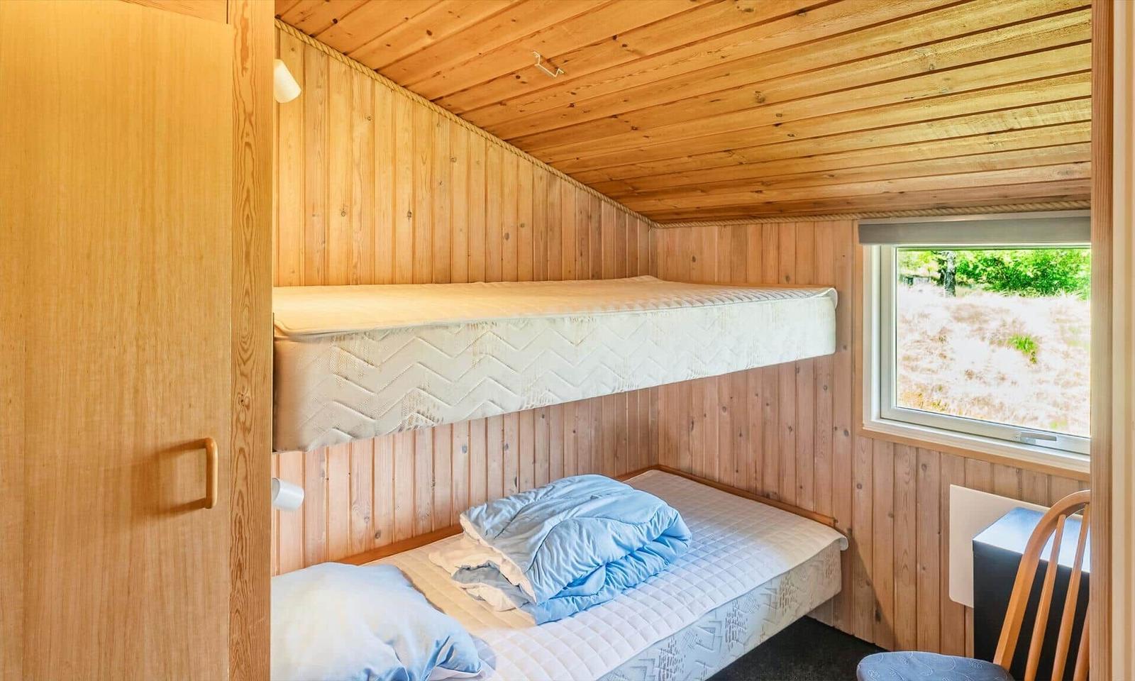 Zimmer mit zwei Matratzen, einer auf der oberen Ebene und einer auf der unteren Ebene.