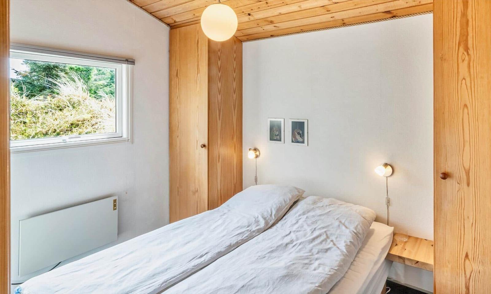 Schlafzimmer mit Bett, Fenster und Holzelementen.
