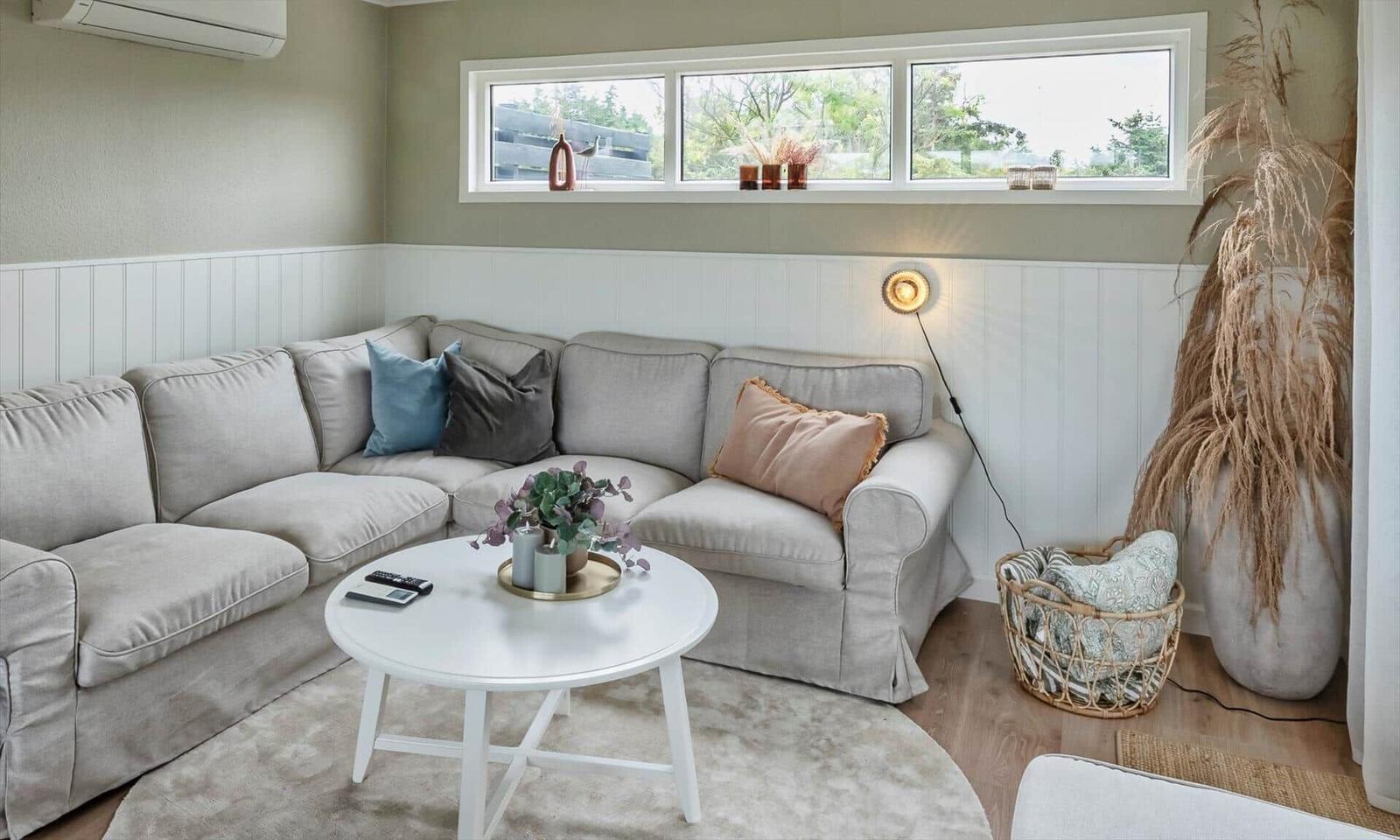 Living room with corner sofa, round table, and windows overlooking outside.