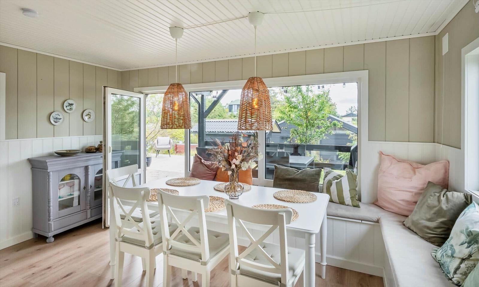 Dining room with white table, chairs, and window seat with cushions.