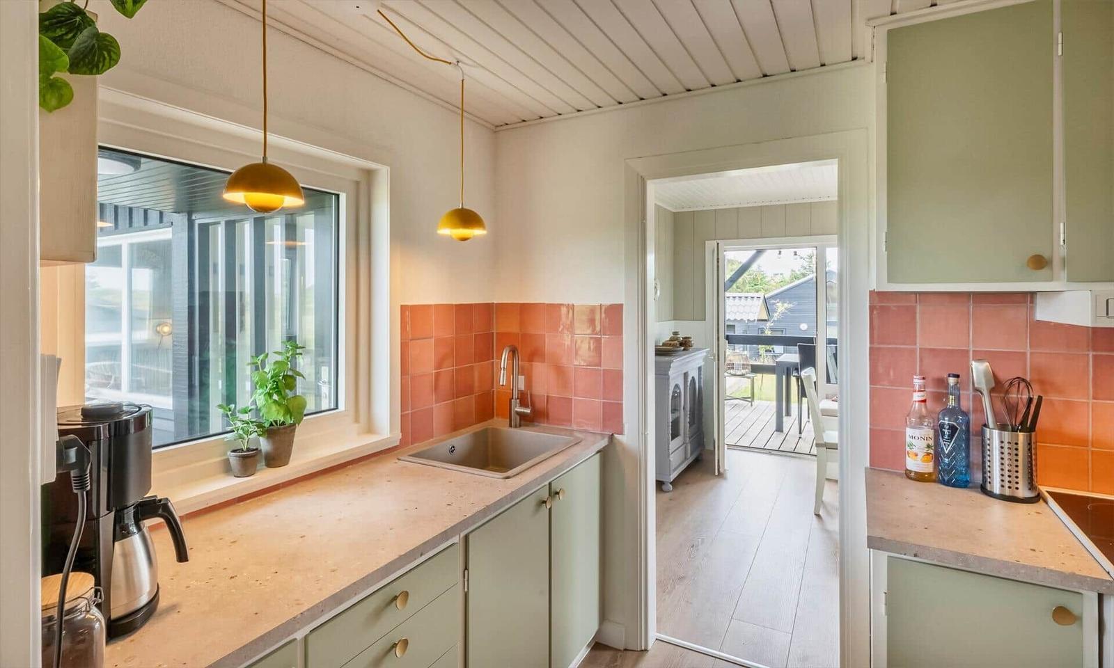 Kitchen with worktop, sink, and window. Passage to living area with terrace.