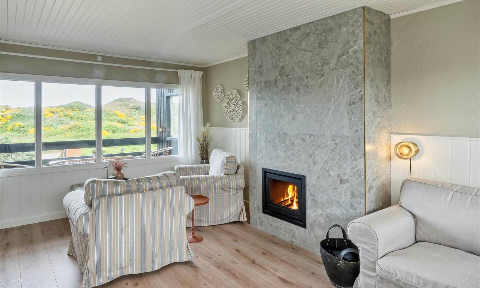 Living room with fireplace, seating, and view of green hills.