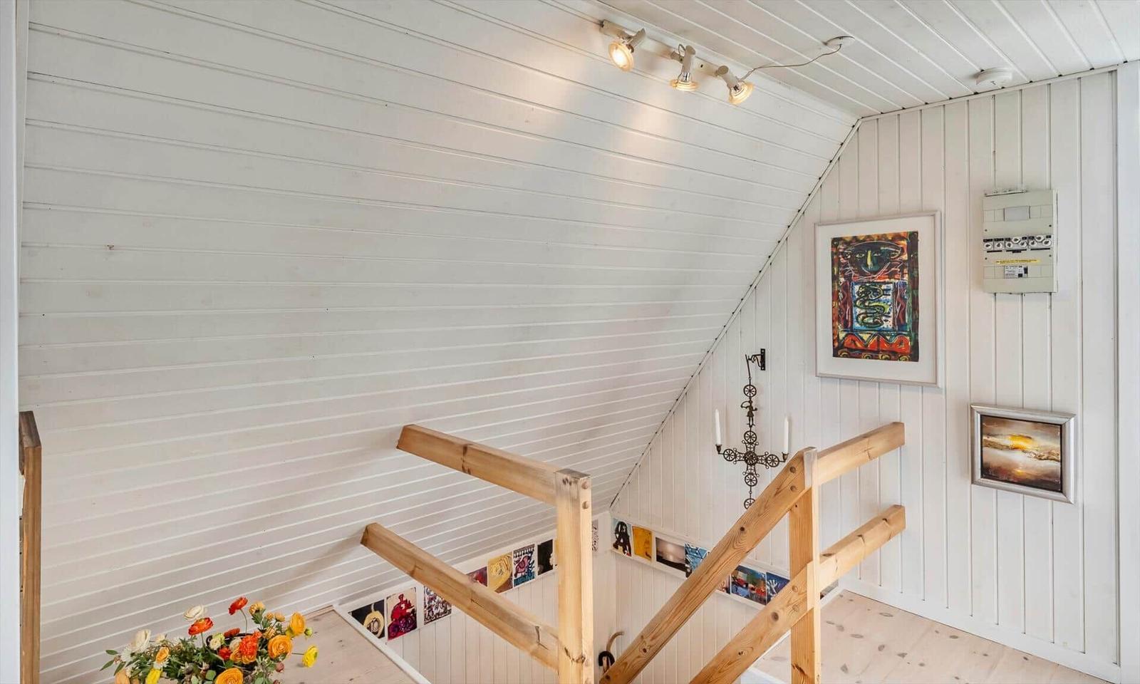 Haus mit Holzgeländer, weißen Wänden und Kunstwerken an der Wand.