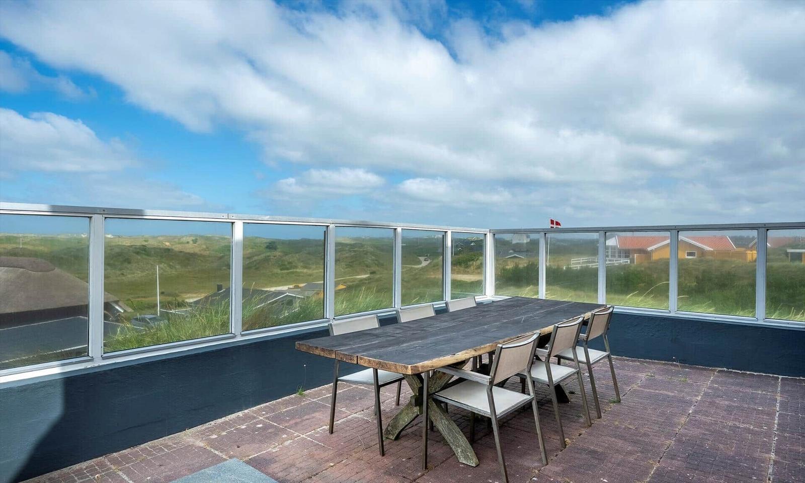 Terrasse mit Tisch und Stühlen, Blick auf Dünen und Häuser