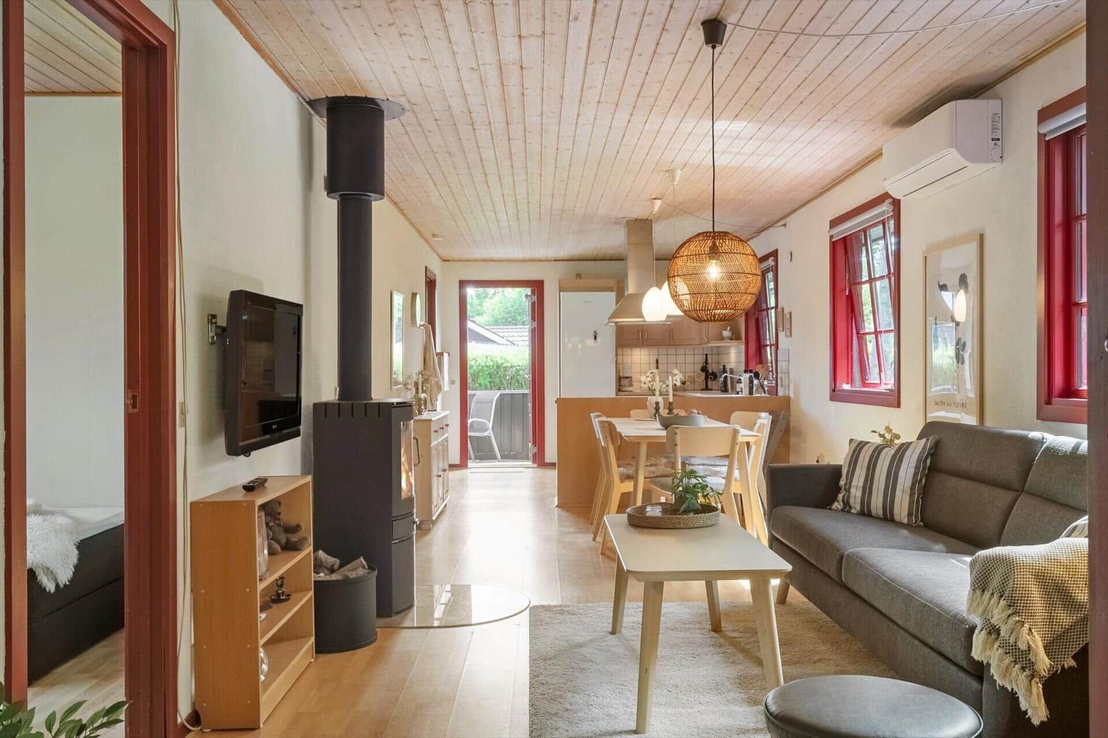 Living area with sofa, dining table, and wood stove. Kitchen and bedroom are visible.