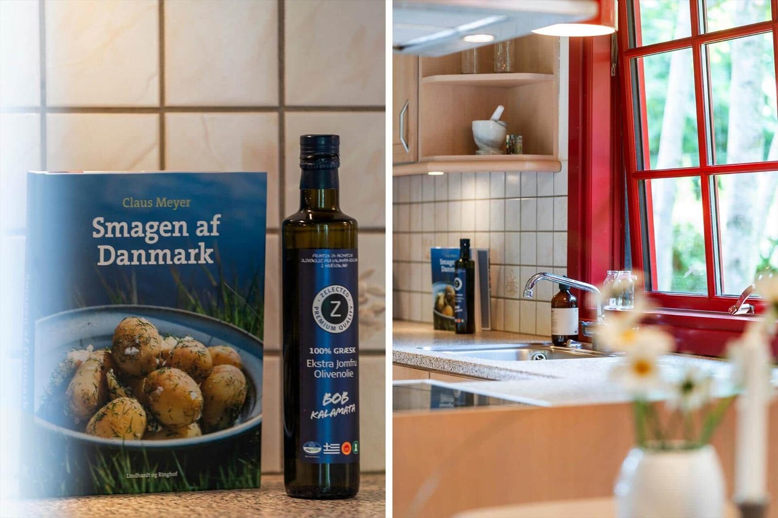 Kitchen with red window, countertop, cookbook, and olive oil bottle.