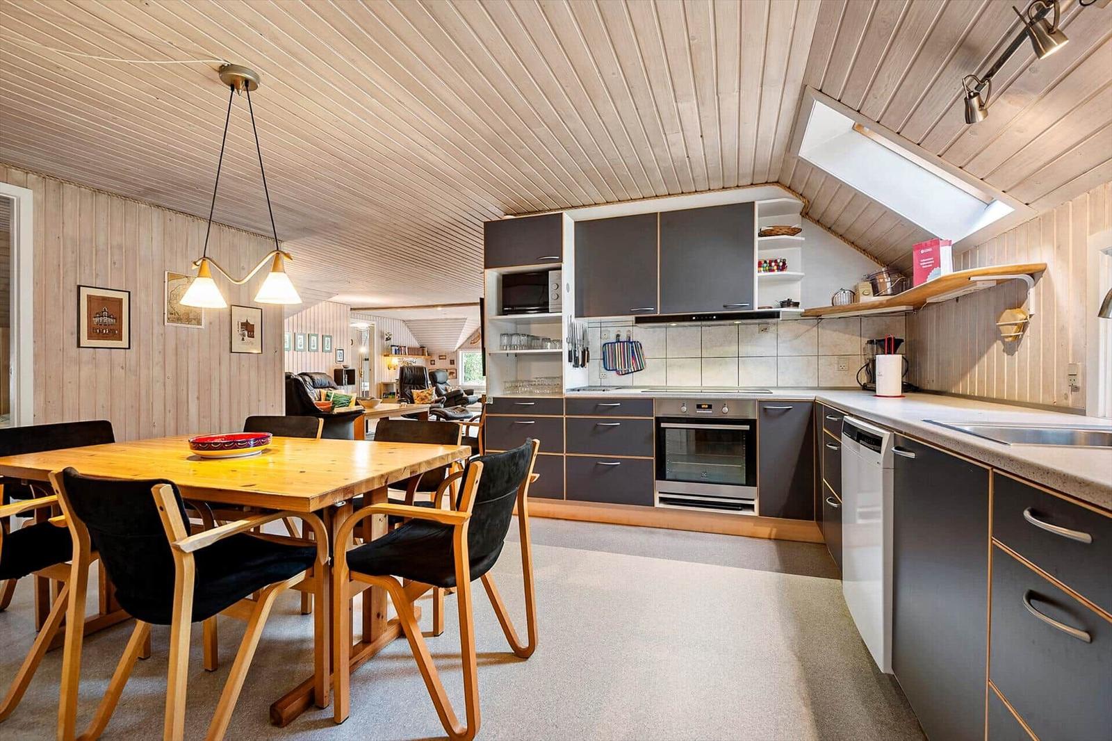 Küche mit Esstisch und Esszimmer. Holzwände und -decke. Einbauküche mit Dunstabzug.