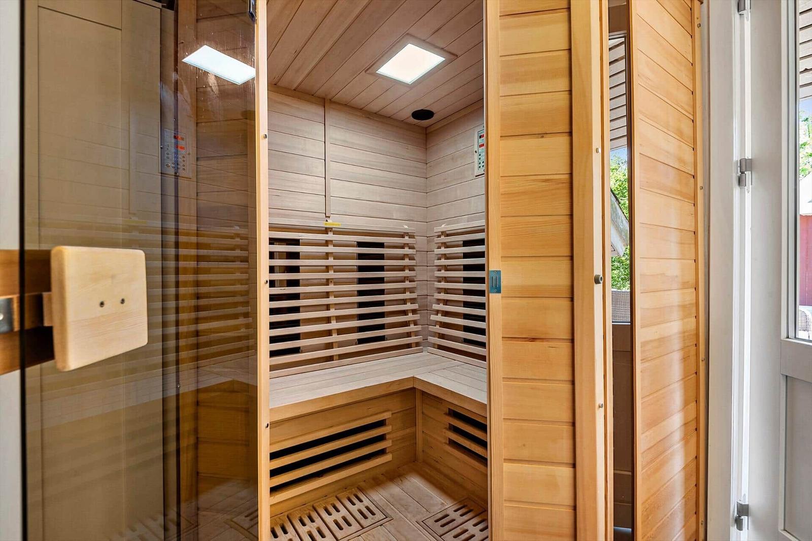 Eine Holzsauna mit Sitzbänken und Glasfront. Die Wände sind mit Holz verkleidet.
