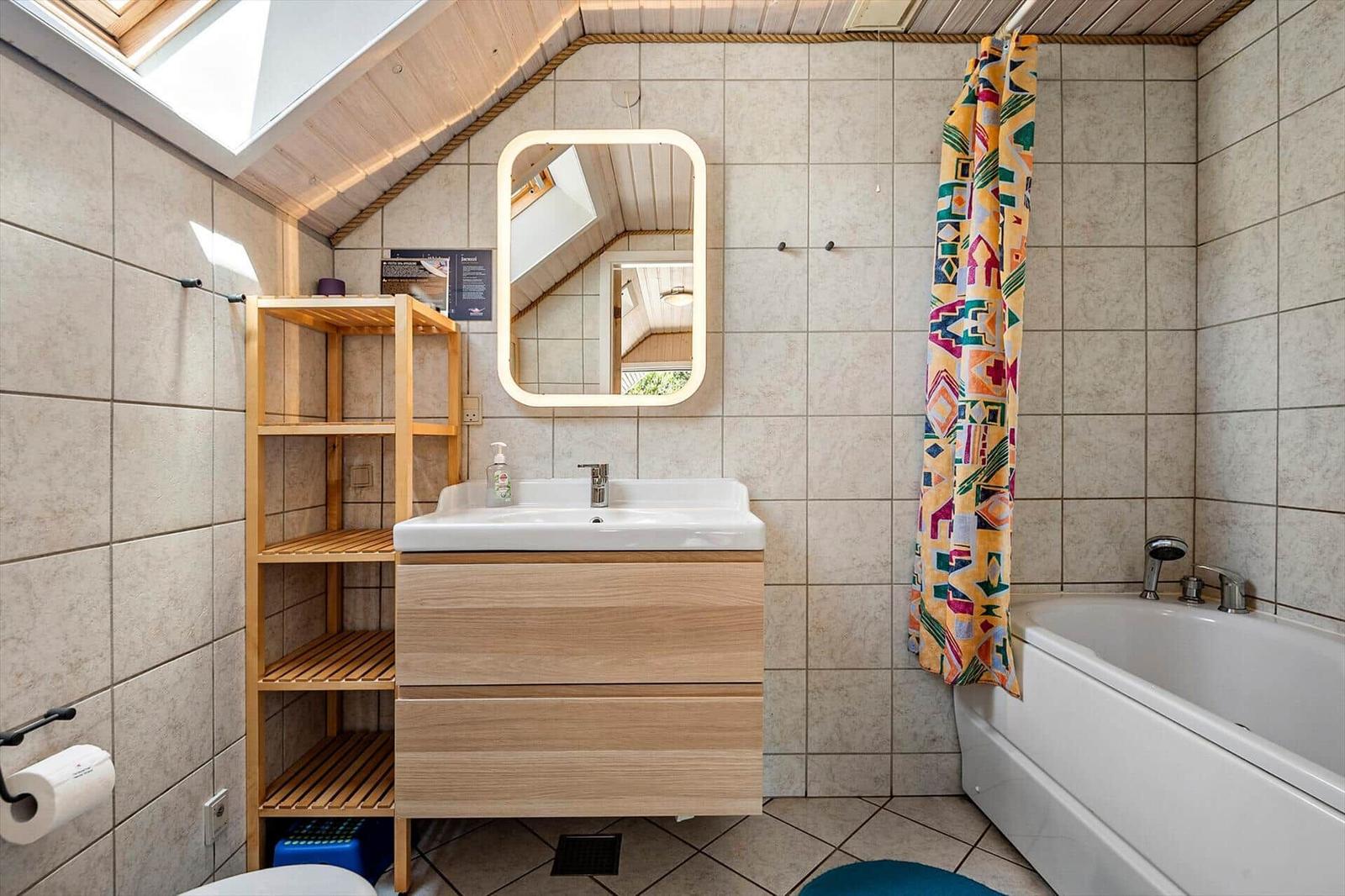 Badezimmer mit Dusche, Badewanne, Spiegelschrank und Holzregal.