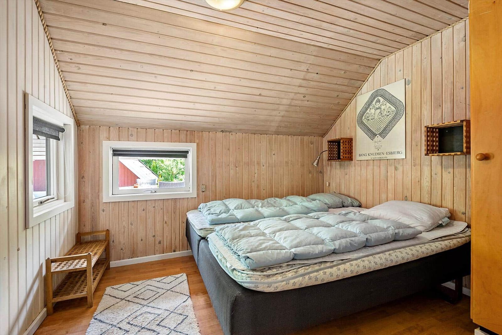 Schlafzimmer mit Holzwänden, Bett, Fenster und Wandbild.
