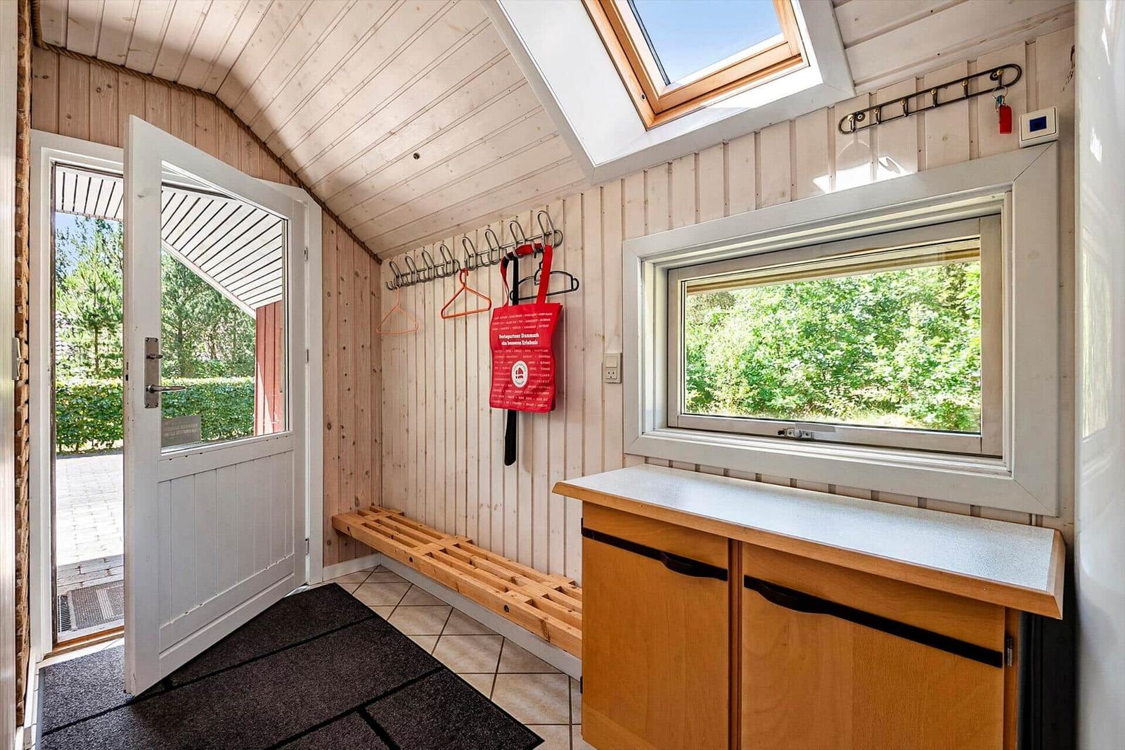 Eingangsbereich mit Holzwand, Fenster, Schrank und Haken für Jacken.