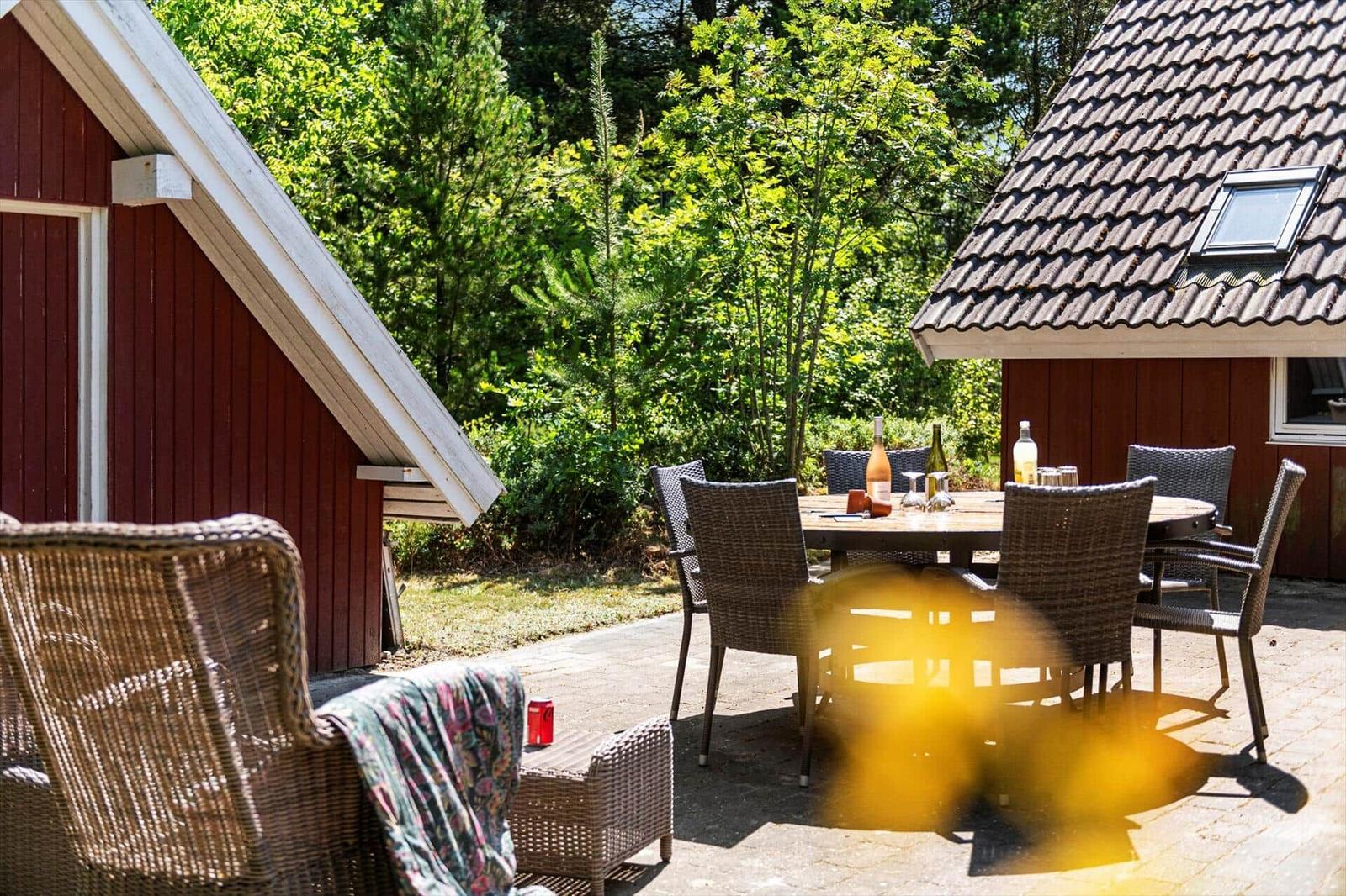 Roter Holzaufbau mit Terrasse, Gartenmöbel und Tisch mit Getränken.