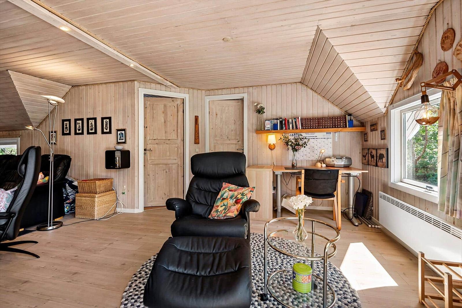 Zimmer mit Holzwand, Schreibtisch, Sessel und Fenster