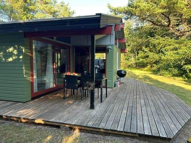 Haus mit Terrasse, Tisch, Stühlen und Grill im Grünen.