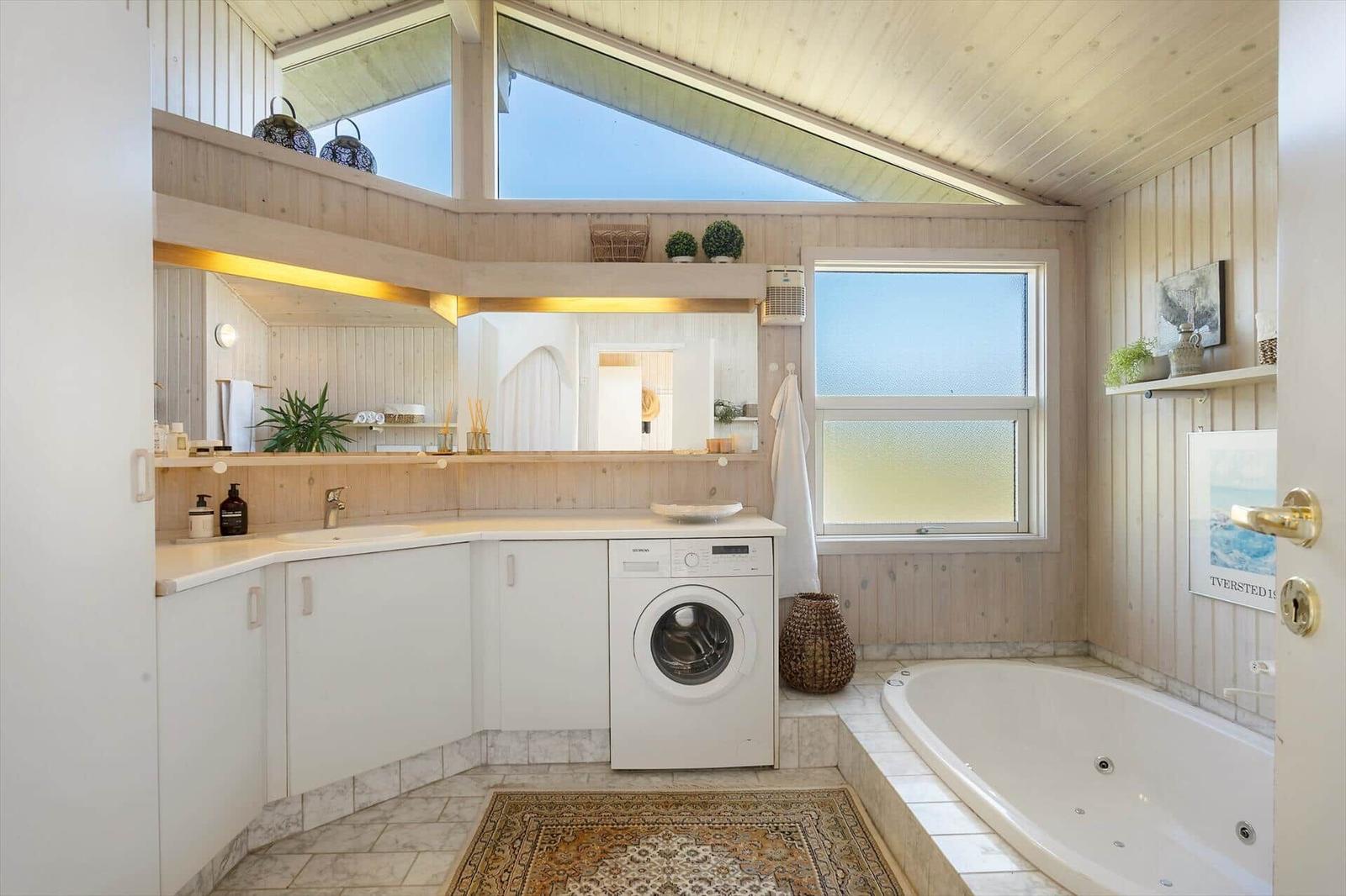 Badezimmer mit Badewanne, Waschmaschine und großen Fenstern