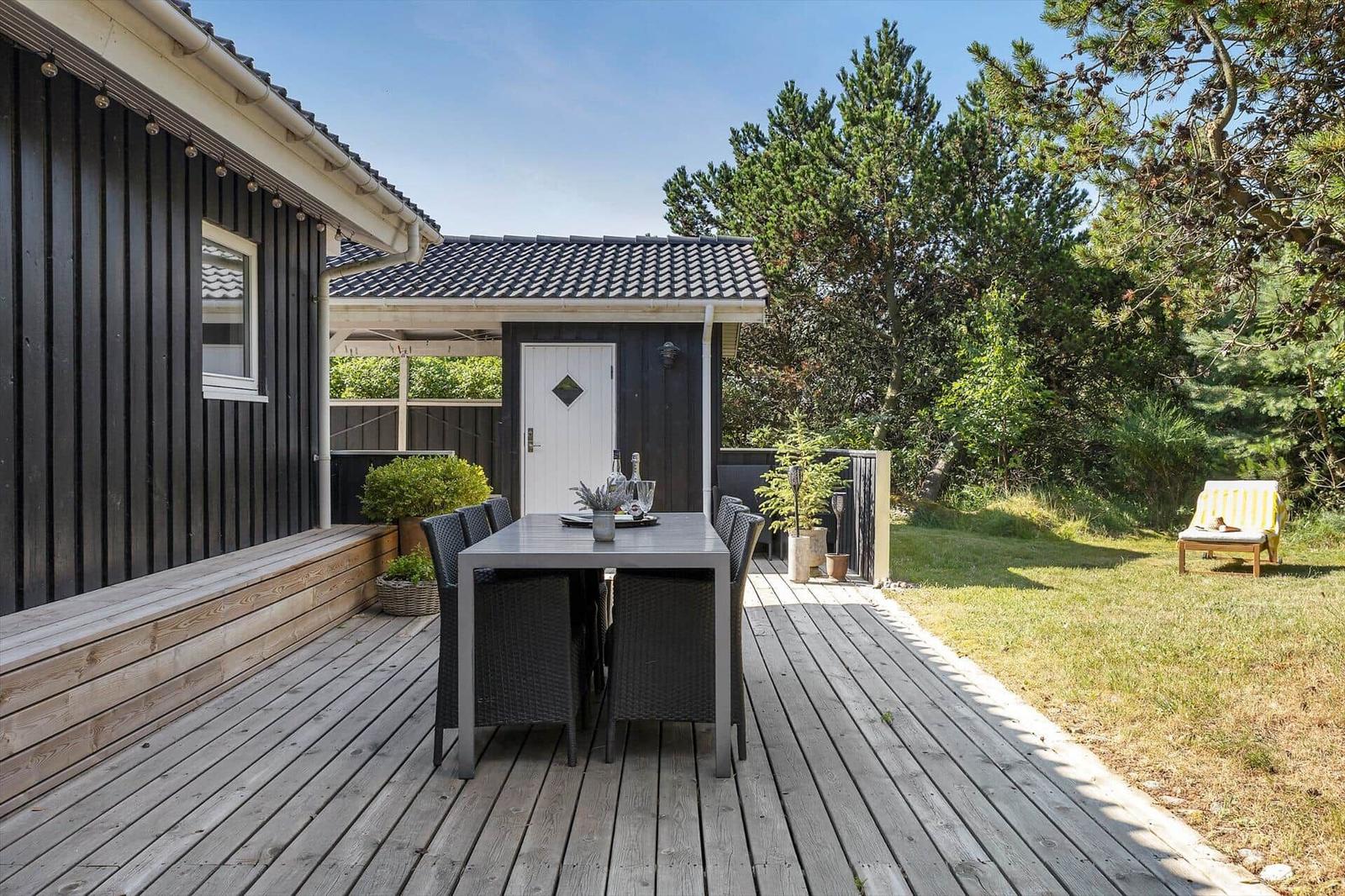 Terrasse mit Tisch und Stühlen neben einem Haus mit Garten.