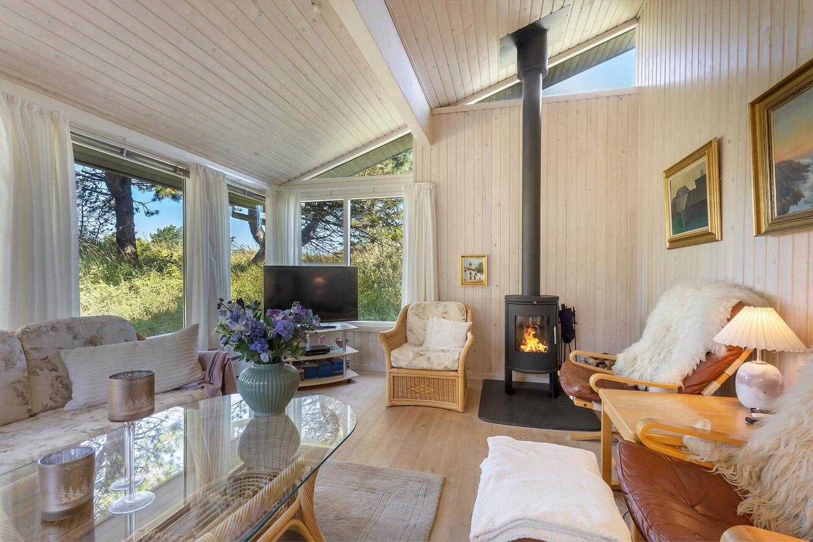Wohnzimmer mit Kamin, Sofa, Sessel und großen Fenstern zur Aussicht.
