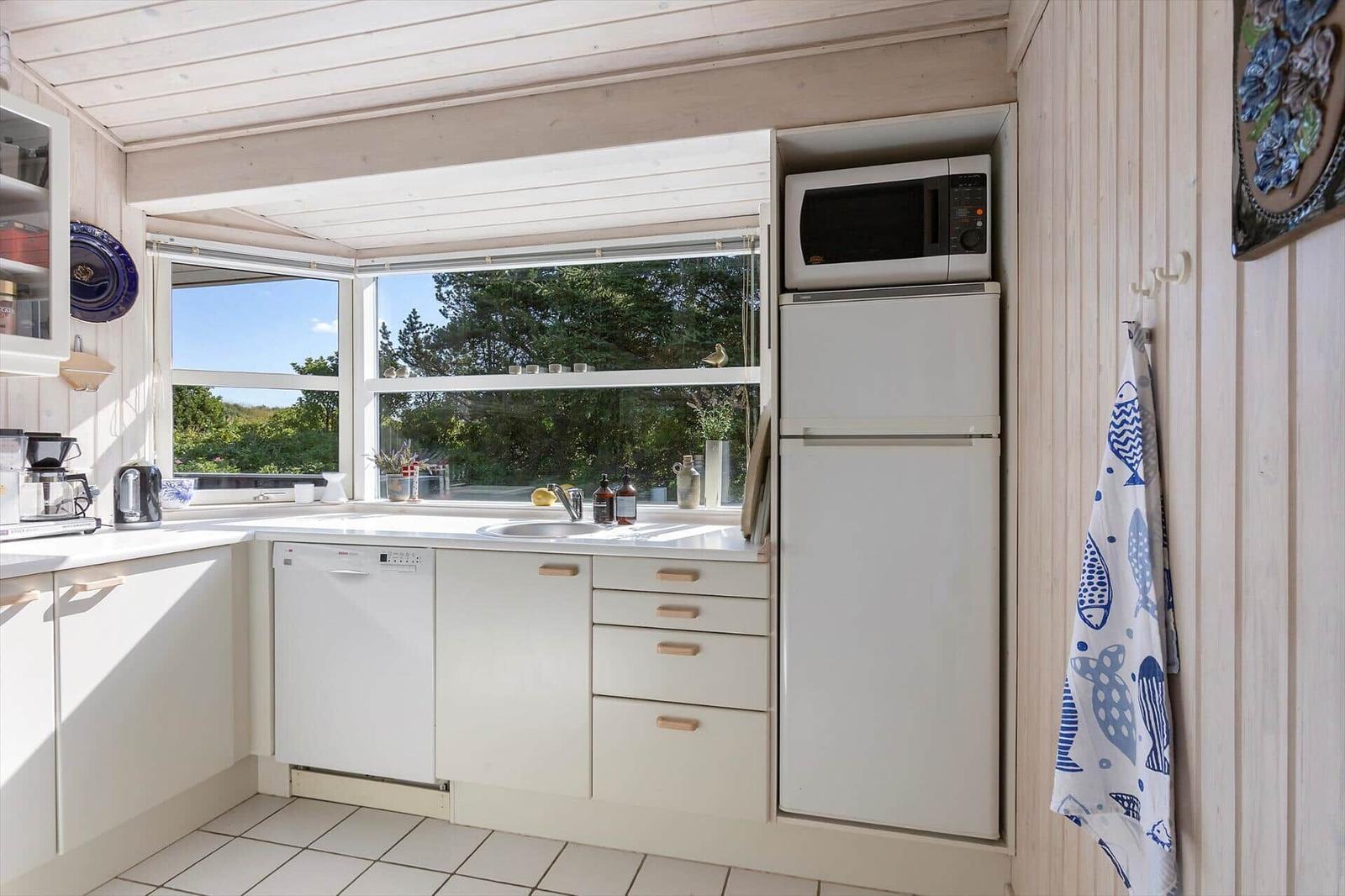 Küche mit Fenster, Spüle, Kühlschrank, Mikrowelle und Waschmaschine.