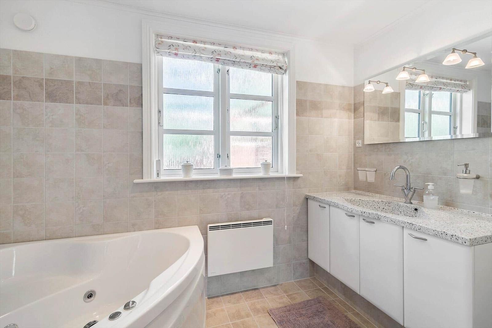 Bathroom with bathtub, sink, and window.