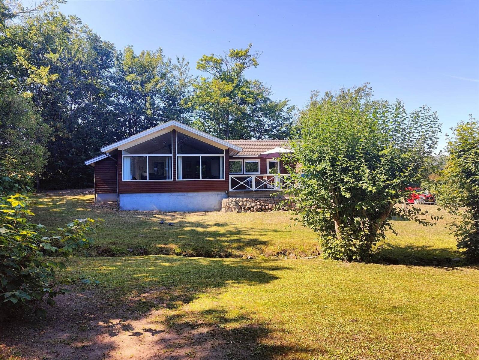 A house with a terrace and green lawn surrounded by trees.