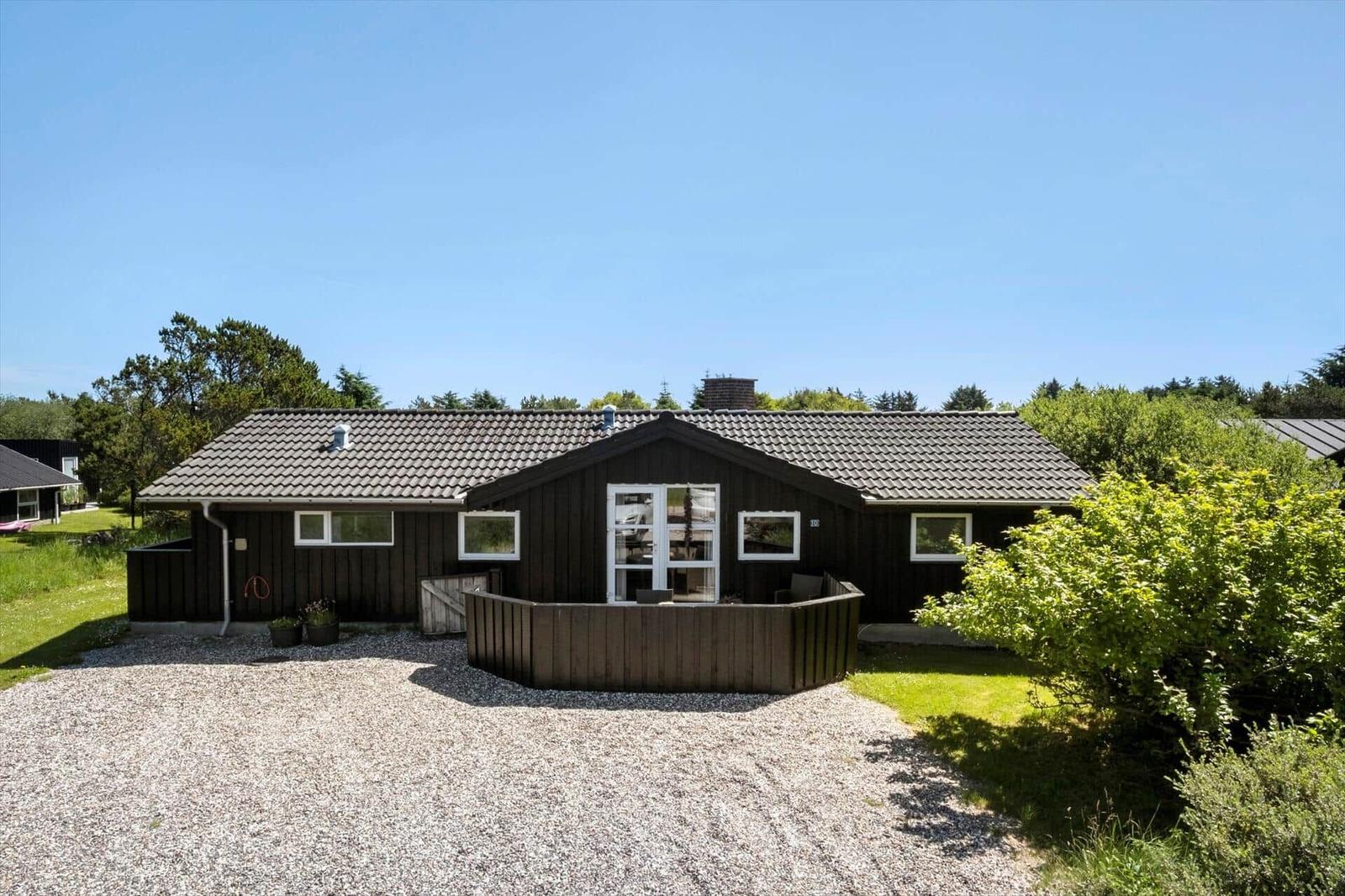 Holzhäuser mit Terrasse und Garten unter blauem Himmel.