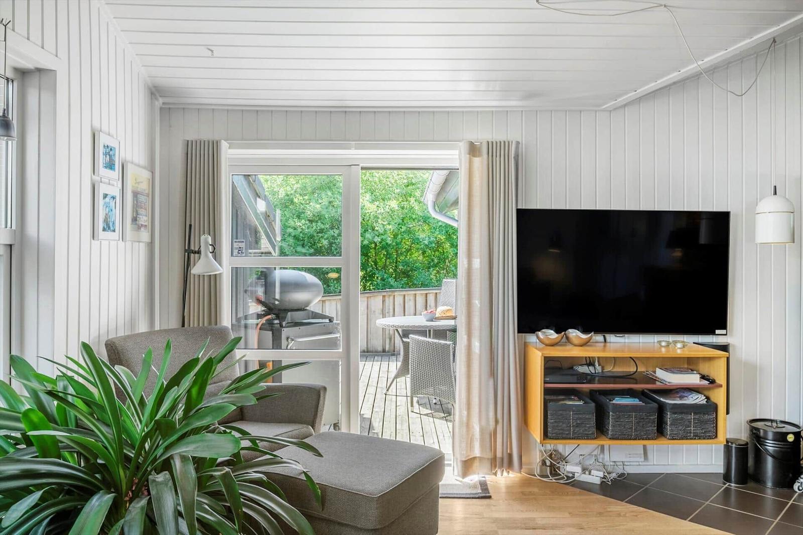 Wohnzimmer mit TV, Sitzgelegenheit und Blick auf die Terrasse.