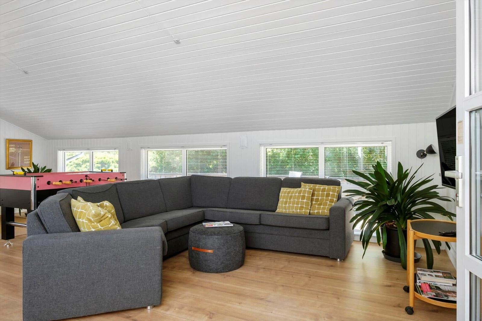 Großer Wohnbereich mit grauem Sofa, Fußbodenheizung und Fenstern.