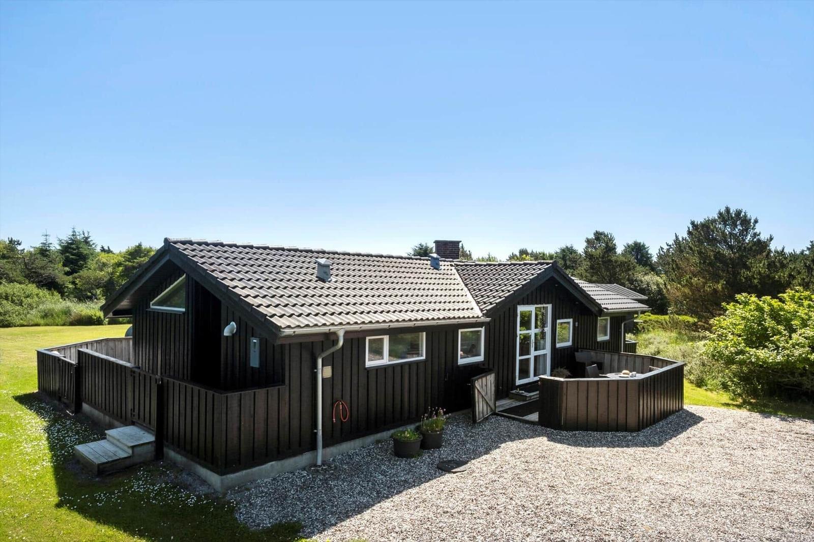 Holzhäuschen mit Terrasse und Garten. Grasfläche und Bäume umgeben die Unterkunft.